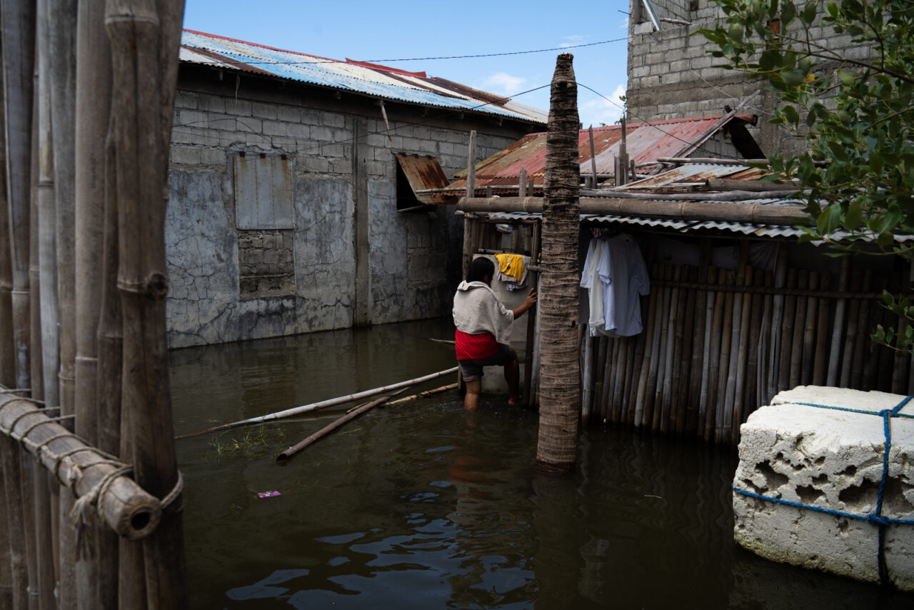 A resident wades through floodwater surrounding closely packed homes in Batang Dos, Sasmuan.
